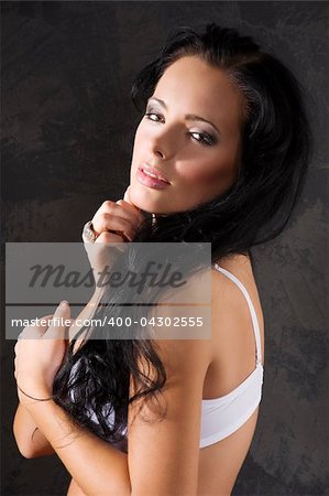 fashion close up portrait of young pretty brunette with white bra against a dark background