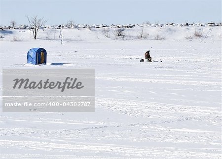 An ice fisherman on a frozen lake.