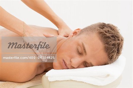 Young blond man enjoying massage session in spa resort