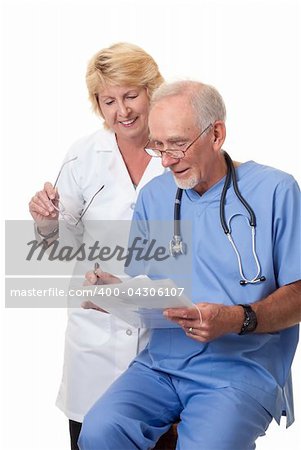 Woman doctor looking over seated male surgeon's notes. They are in discussion.  She is wearing a white coat, while he is in blue scrubs. Isolated on white background.