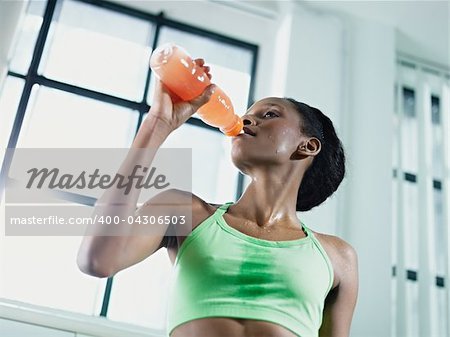 young african american woman in sportswear with energy drink in gym. Horizontal shape, waist up, low angle view