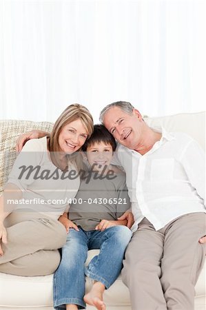 A little boy with his grandparents looking at the camera at home