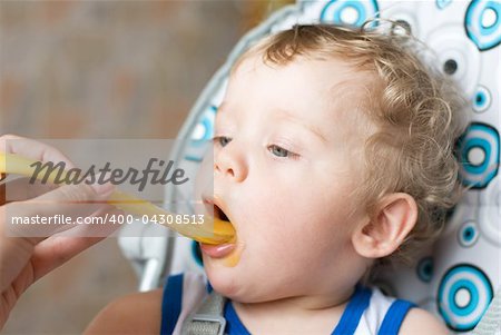 Petit garçon avec une cuillère à la main mum d'alimentation