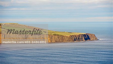 Cliffs on a coastline with flat seas on a clear day