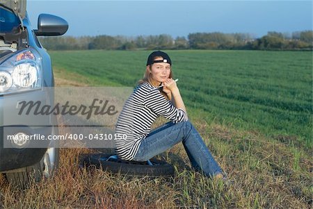 young blond woman with her broken car. The girl is angry