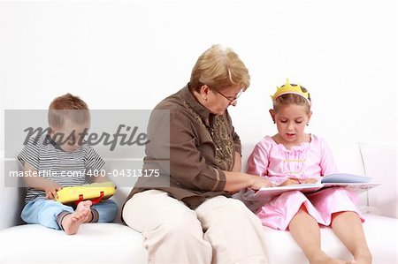 Grandma helping gorl by reading and playing with baby