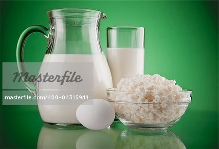 jug with milk and curds on green background