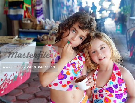 beautiful sisters  little girls eating chocolate ice cream in mexican market