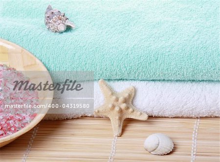 Stack of soft towels with starfish and bath salt on bamboo mat