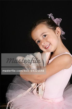 Cute brunette ballet girl holding lots of pointe shoes