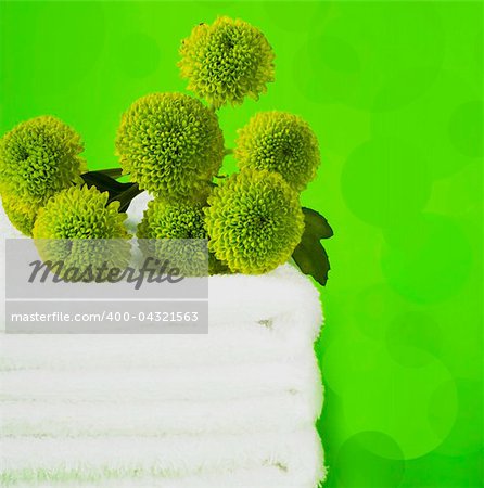 Pile white towels on green background and   branch chrysanthemums