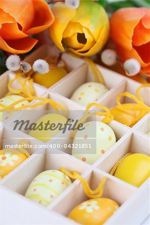 Yellow Easter eggs in a box and colorful tulips. Shallow dof