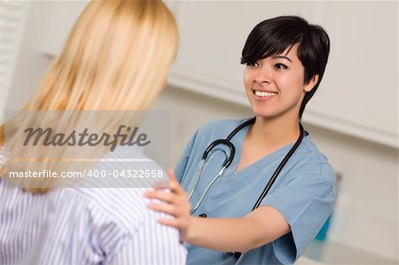 Smiling Attractive Multi-ethnic Young Female Doctor or Nurse Wearing Scrubs and Stethoscope Talking with Patient.