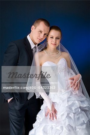 Bride and groom studio portrait over blue background
