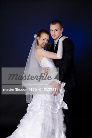 Bride and groom studio portrait over blue background