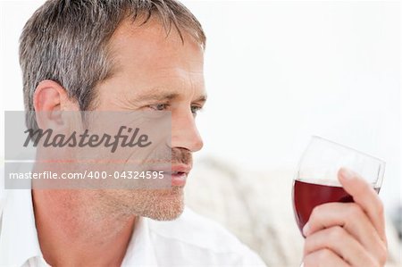 Handsome man drinking some red wine at home