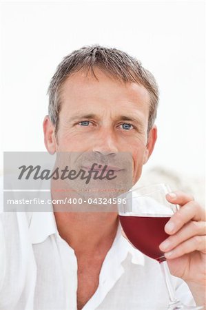 Handsome man drinking some red wine at home