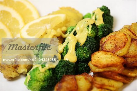 A close-up of fried cod with sliced potatoes, broccoli and bechame sauce