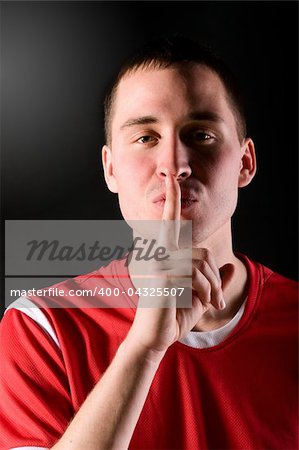 football player is showing quiet gesture in dark