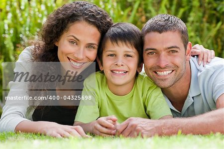 Little boy with his parents lying down in the garden