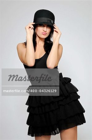 Beautiful fashion model in black dress with evening make-up and hat