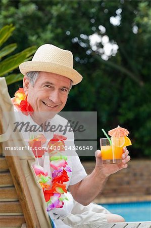Mature man drinking a cocktail  beside the swimming pool