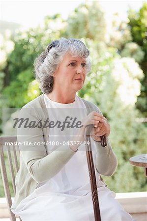 Retired woman with her walking stick at home