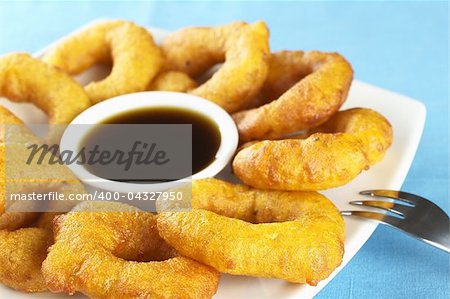 Popular Peruvian dessert called "picarones" made from squash and sweet potato and served with "chancaca" (kind of honey) syrup (Selective Focus, Focus on the front)