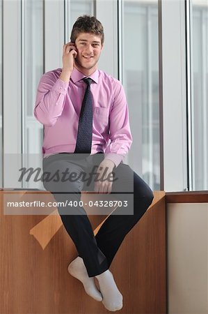 young business man talk by cellphone over bright window in big hall