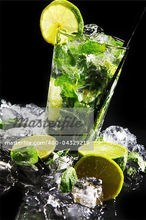 Fresh drink with ice, green mint and lime on black background