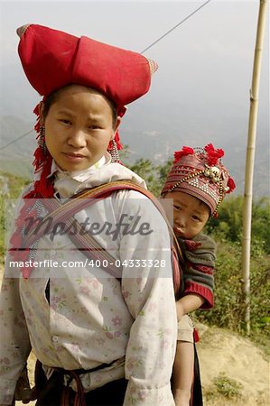 Nearly SAPA, City of North Vietnam. A woman of the ethnic (minority) Hmong Red pompoms with her baby in the back. She wears her beautiful costumes and hairstyle typical. Her baby was also a traditional cap color