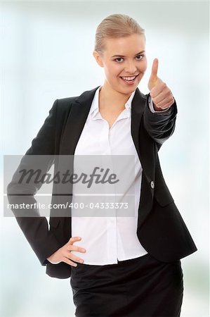 Young business woman showing OK sign, looking at camera and smiling.
