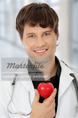 Handsome young male doctor holding heart shape toy