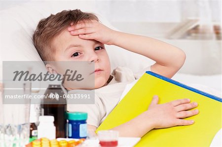 Sick little beautiful boy with book in the bed