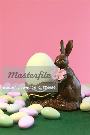Chocolate Easter bunny holding egg with pastel candy