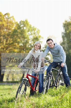 Young smiling couple on bicycles in the park