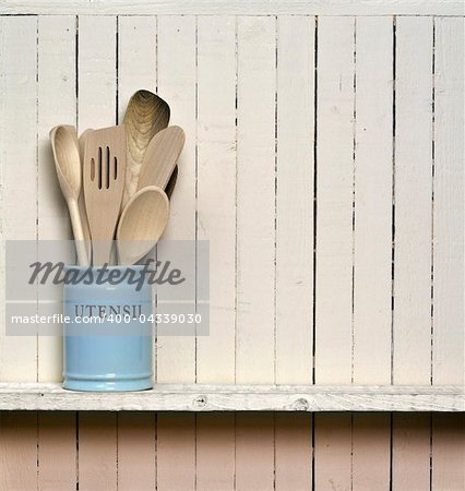 Kitchen cooking utensils; wooden spatulas etc in jar on shelf in front of rustic wall; wall allows good copy-space