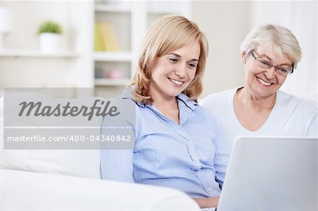 Smiling mother and daughter looking at laptop