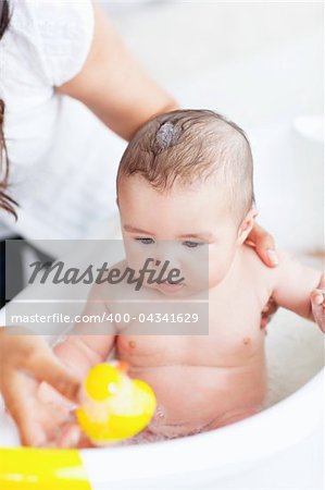 Adorable baby taking a bath wihile his adorable mother takes care of him at home