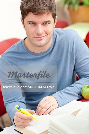 Portrait of a smiling male student working in the library of his university