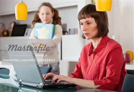 Mother and teenager girl with laptop computer together at home