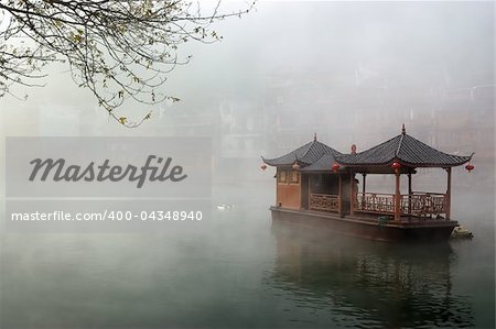 China landscape of boat on foggy river with traditional building background in Hunan province