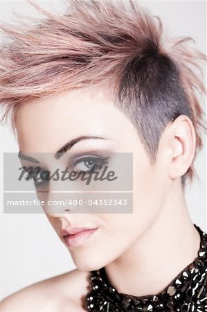 An attractive young female with a serious expression is wearing a punk hairstyle with pink hair. Vertical shot.