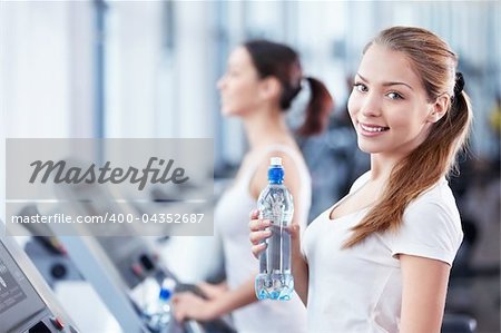 Young girl with a bottle of water on the treadmill