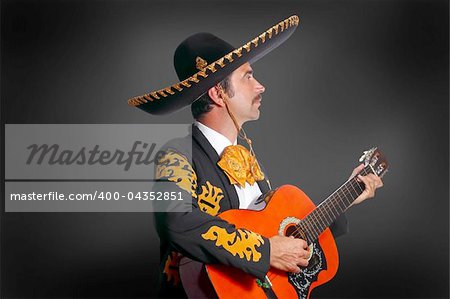 Charro Mariachi playing guitar on black background