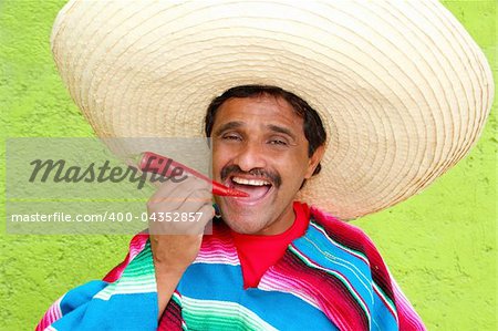 Mexican man poncho sombrero eating red chili hot pepper Mexico