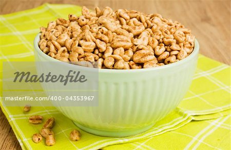Sweet popped wheat grains in bowl on wooden background