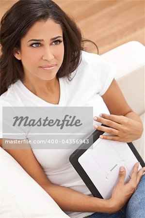 Portrait of a beautiful young Latina Hispanic woman or girl looking thoughtful and using a tablet computer