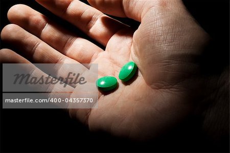 Two green pills on the opened palm
