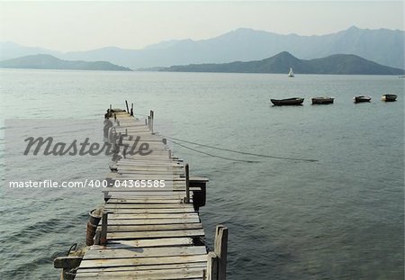 wooden pier with boats in the distance